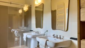 a bathroom with three sinks and two mirrors at Masseria Celeste in Fasano