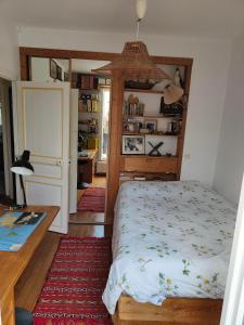 Schlafzimmer mit einem Bett, einem Tisch und einem Schreibtisch in der Unterkunft Rez de chaussée et 1er étage et jardin dans Maison individuelle in Enghien-les-Bains