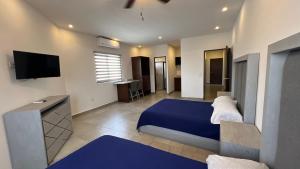 1 dormitorio con 1 cama azul y TV de pantalla plana en Hotel Plazuela, en Cadereyta Jiménez