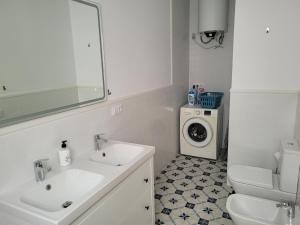 Casa con WiFi, patio y garaje privado في ألكالا دي غواديرا: حمام مع مغسلة وغسالة ملابس