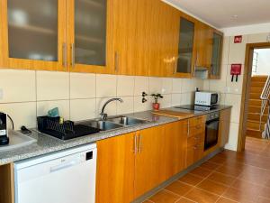 una cocina con armarios de madera y fregadero en Vila Noélia en Albufeira
