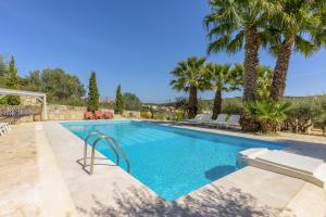 a swimming pool with palm trees in a villa at The Olive Grove Villa with private swimming pool in Archanes