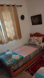 a bedroom with a small bed and a window at j appartement in Essaouira