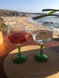 two wine glasses sitting on a table with a beach at A casa do Almograve in Almograve