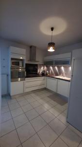 una cocina con armarios blancos y electrodomésticos de acero inoxidable en Le cocoon paisible avec garage au pied du Corbusier, en Firminy