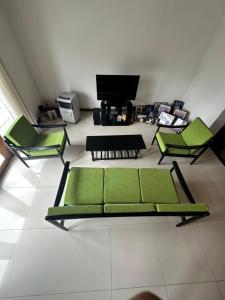a living room with green chairs and a television at Kande Home in Kandy