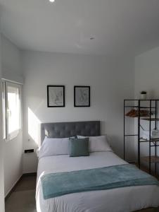een slaapkamer met een bed met twee foto's aan de muur bij El Merendero in Utrera