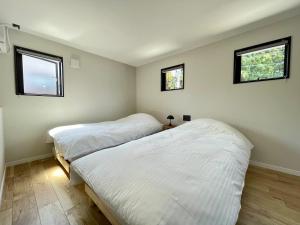 two beds in a room with two windows at Spruce Cottage in Yuzawa