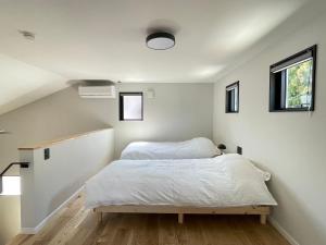 a bedroom with a bed and two windows at Spruce Cottage in Yuzawa