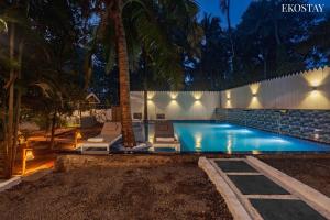 a swimming pool with two lounge chairs and a palm tree at Ekostay Jungle Beach Villa I 1 Acre Property I 100 Meters from the Beach in Alibaug
