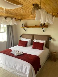 カンポス・ド・ジョルドンにあるPousada Ville Le Montのベッドルーム(赤い枕の大きな白いベッド付)