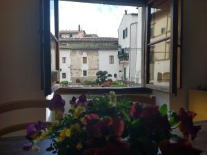 um vaso de flores sobre uma mesa em frente a uma janela em Palazzo Reali Apartment - Camera nella storia di Pistoia em Pistoia