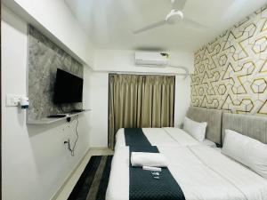 a hotel room with a bed and a flat screen tv at Astha Powai Service Apartment in Mumbai