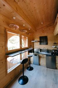 a kitchen with two bar stools in a log cabin at Charming Tiny House in LʼIsle-sur-la-Sorgue