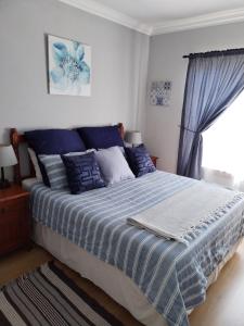 a bedroom with a blue and white bed with a window at Jan's Cottage in Centurion