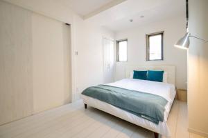 ein weißes Schlafzimmer mit einem großen Bett mit blauen Kissen in der Unterkunft オーシャンズスイート 東京ディズニーリゾートマリンバルコニー303室 in Tokio