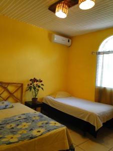 two beds in a room with yellow walls and a window at Hotel Caleta in San Miguel