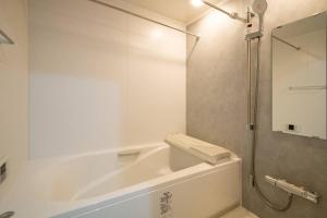 東京的住宿－オーシャンズスイート 東京ディズニーリゾートマリンバルコニー303室，白色的浴室设有浴缸和淋浴。