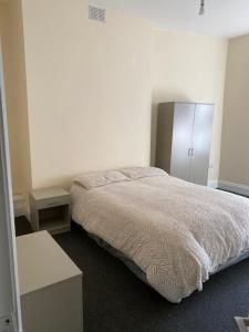 a white bedroom with a bed and a cabinet at Manchester Stay in Farnworth