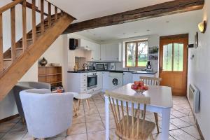 a kitchen with a white table and chairs at La petite maison bleue in Les Portes du Coglais