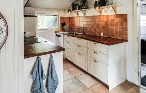 a kitchen with white cabinets and a sink at Four-Bedroom Holiday Home In Vaggerlose in Marielyst