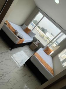 2 camas en una habitación con ventana grande en HOTEL LUXEM, en Bogotá