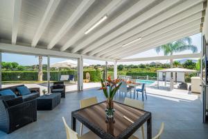 ein Wohnzimmer im Freien mit Tisch und Stühlen in der Unterkunft Villa Dell'Ulivo con piscina privata By Sicily Home Solutions in Alcamo