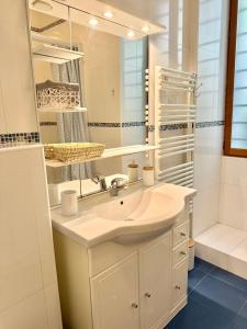 La salle de bains blanche est pourvue d'un lavabo et d'un miroir. dans l'établissement Le St Julien Terrasse vue mer exceptionnelle, à Menton