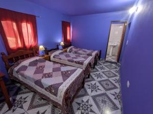 a blue room with two beds and a mirror at Hostal Mary in Iruya