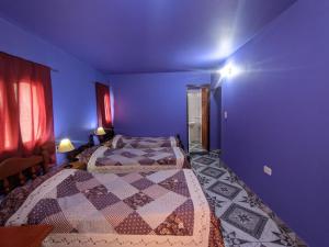 een slaapkamer met 2 bedden en een blauwe muur bij Hostal Mary in Iruya