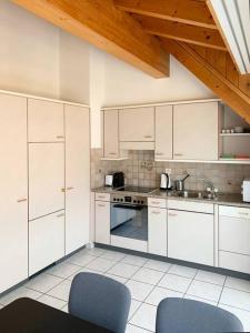 a kitchen with white cabinets and two blue chairs at Charming penthouse with veranda in the center of Brig in Brig