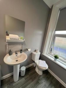baño con lavabo y aseo y ventana en Alexander Hotel, en Whitley Bay