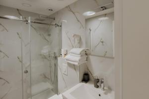 a white bathroom with a shower and a sink at Lux City Apartments & Rooms in Sarajevo +85 photos