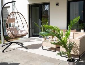 a swing and a chair on a patio with plants at Fairmieten: Exklusive Suite I Terrasse I Parkplatz in Bielefeld
