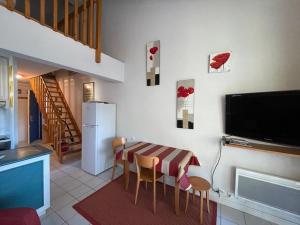 a kitchen with a table and chairs and a television at Appartement Soustons, 2 pièces, 4 personnes - FR-1-379-110 in Soustons