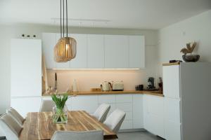 a kitchen with a wooden table and white cabinets at Fairmieten: Exklusive Suite I Terrasse I Parkplatz in Bielefeld