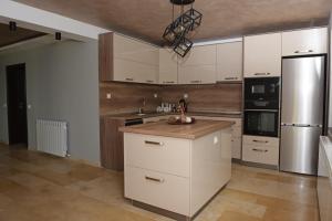 a kitchen with white cabinets and a stainless steel refrigerator at Вила Релакс in Pamporovo