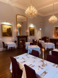 uma sala de jantar com mesas e cadeiras brancas e lustres em Kinnitty Castle Hotel em Kinnitty