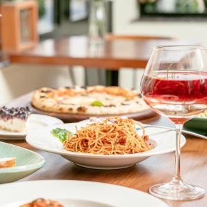 a table with plates of pasta and a glass of wine at LP Residency in Dehradun