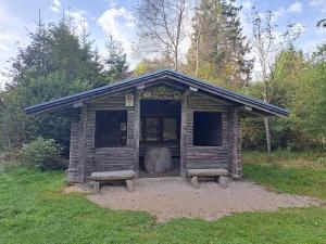 un pequeño edificio de madera con dos bancos en un campo en Androla am Vennbahnradweg, en Monschau