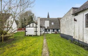 an old house with a grass yard next to a building at 2 Bedroom Beautiful Home In rskbing in Ærøskøbing