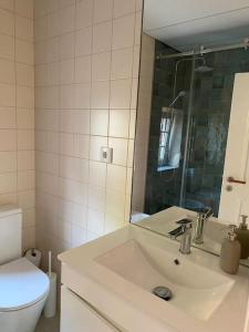 een badkamer met een wastafel, een toilet en een spiegel bij Charming house close to Sintra in São Martinho