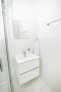 a white bathroom with a sink and a mirror at Quattro City Center Ap 501B in Larnaka