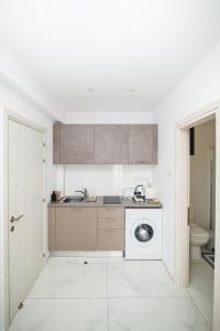 a white kitchen with a sink and a washing machine at Quattro City Center Ap 501B in Larnaka