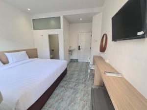 a hotel room with a bed and a flat screen tv at Triple D Hotel in Betong