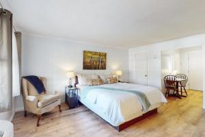 Un dormitorio blanco con una cama y una silla. en Dogwood - Unit 603, en Flat Rock