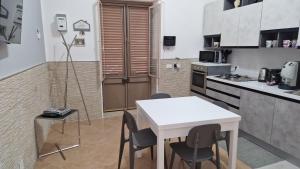 Il comprend une petite cuisine avec une table et des chaises blanches. dans l'établissement The brothers house Appartamento alla Zisa, à Palerme