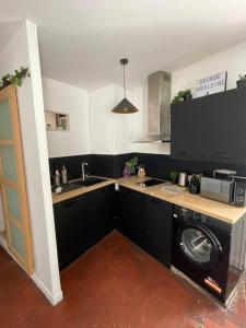 a kitchen with black cabinets and a washer and dryer at La Grande Madeleine in Nantes