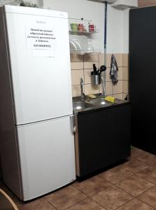 La cuisine est équipée d'un réfrigérateur blanc et d'un évier. dans l'établissement GO Hostel Rewolucji, à Łódź