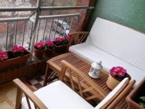 a balcony with a bench and chairs and potted plants at Rózsadomb apartman in Pécs